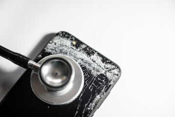 black mobile phone with broken screen and stethoscope,selective focus.Cell phone crash screen cracked.