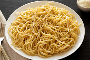 Homemade Cacio E Pepe Pasta with Pecorino Romano and Pepper on a white plate on a black background, side view.