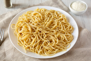 Homemade Cacio E Pepe Pasta with Pecorino Romano and Pepper on a white plate, low angle view.