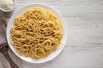 Homemade Cacio E Pepe Pasta with Pecorino Romano and Pepper on a white plate, top view. From above, overhead, flat lay. Space for text.