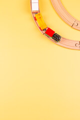 Toy train with curved wooden railways on pastel yellow background. Top view