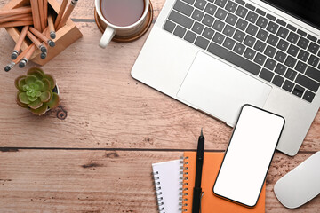 Wood office desk table with laptop, smart phone, coffee cup and supplies.