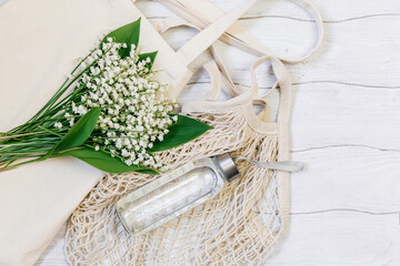 Zero waste concept. Glass water bottles and eco bag on a white wooden table.