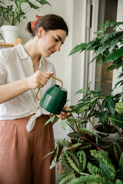 young woman watering home plants