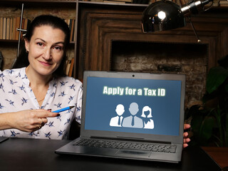Businesswoman holding a laptop. Business concept about Apply for a Tax ID with phrase on the sheet.