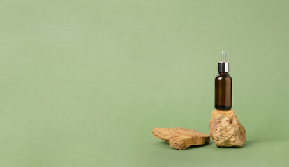 A bottle of serum oil cosmetic on an abstract podium made of natural materials stones plants green...