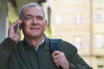 adult man tourist with mobile phone and backpack walking down the street