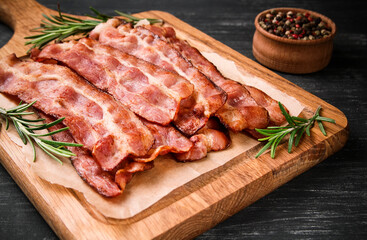 Hot fried bacon with rosemary on a black background.