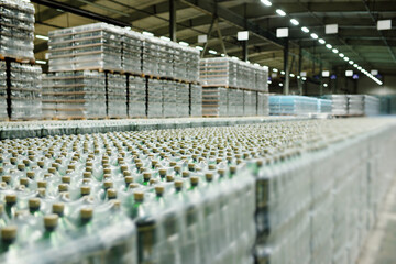 a huge industrial warehouse with plastic food wrap wrapped plastic bottles with carbonated drinks,  water or beer. - obrazy, fototapety, plakaty