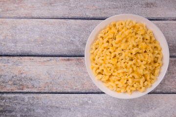 Macaroni and cheese on a white plate on a wooden background