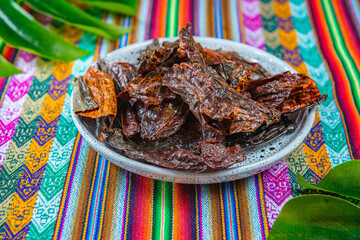 Dried red hot peppers in a blue dish on a colorful peruvian tablecloth 