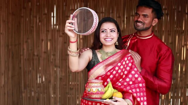 Indian woman celebrating Karva Chauth by looking at her husband after looking at the moon at night