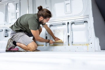 Man attaching insulation on the inside of a van