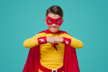 Boy in superhero costume looking at camera in studio
