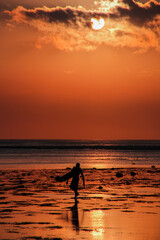 Beautiful sunset over the sea with a silhouette of a surfer
