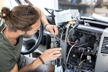 Man working on electronics inside the center console of a car