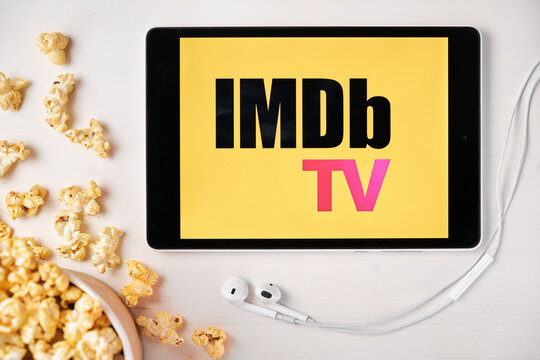 IMDb TV on the screen of the tablet with popcorn box and Apple earphones on the background. Advertising or news content, August 2020, San Francisco, USA