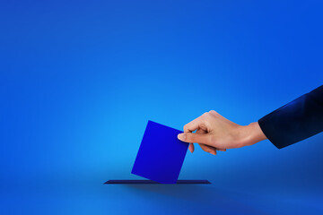 Hand holding ballot paper for election vote concept at blue background.