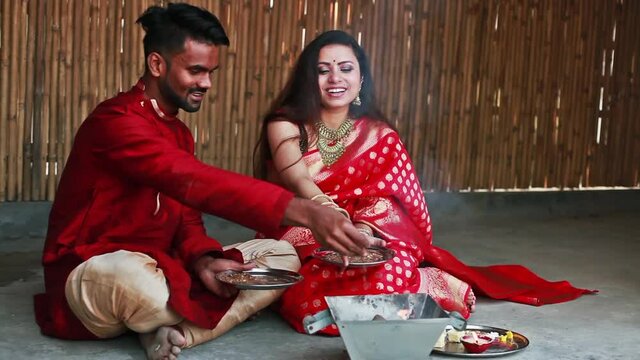 Beautiful Hindu Indian couple in red ethnic clothes praying with hawan on first day of Navratri festival