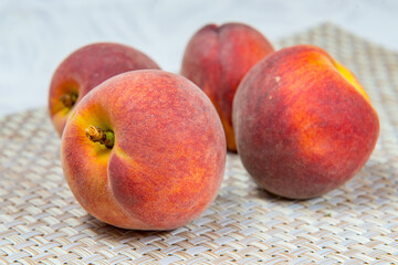 Four ripe peaches on a beige wicker rug