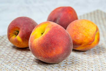 Four ripe peaches on a beige wicker rug