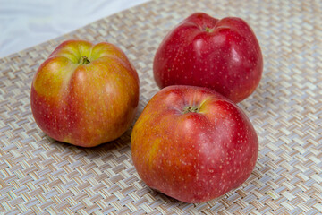 Three ripe apples on a beige wicker mat