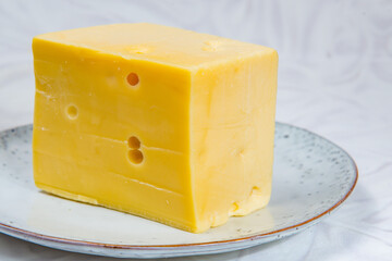 Big piece of yellow cheese on the grey round plate
