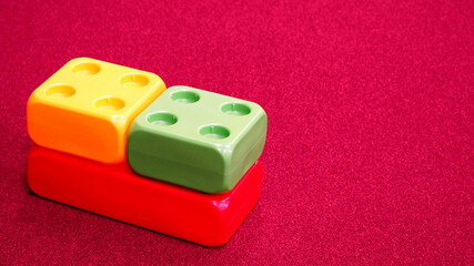 close left large green yellow and pink plastic cubes stands on a pink carpet side view