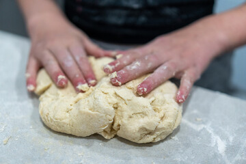 hands kneading dough on marble kitchen bench, baking cinnamon rolls from scratch