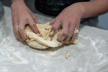 hands kneading dough on marble kitchen bench, baking cinnamon rolls from scratch