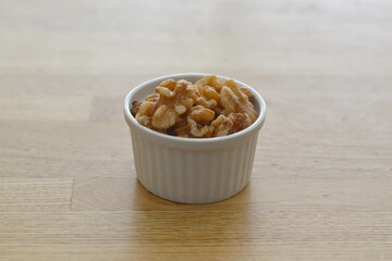 Organic walnuts in a ceramic cocotte on wooden surface