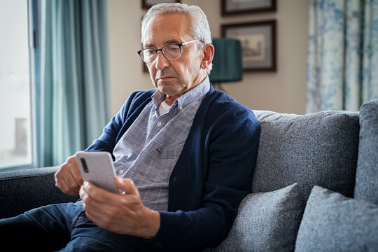 Serious senior man using smartphone