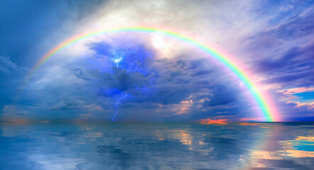 Beautiful landscape with rainbow and lightning over the calm sea at sunset 