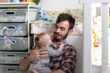 young man in plaid shirt plays with baby in gray suit