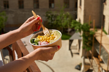 concept of healthy vegan lunch bowl in female hands on the street. Avocado salad and quinoa. food delivery, takeaway