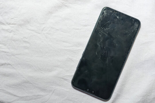 Mobile smartphone screen glass cracked on white cloth