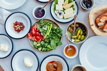 Variety of plates with cheese, butter, vegetables and olives.
