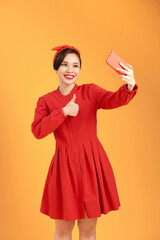 Portrait of a pretty girl taking a selfie isolated over yellow background