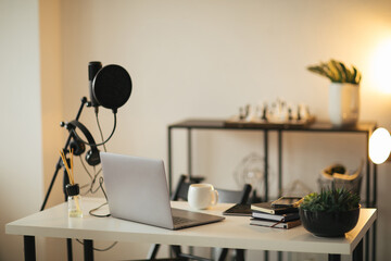 Items for recording podcast: professional microphone, earphones and laptop on white table in studio...