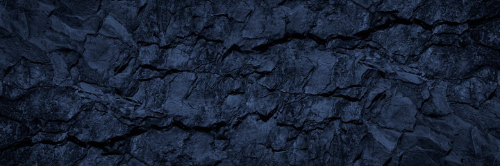 Black blue stone background. Toned rock texture. Wide banner. Dark grunge background with copy space for design. Cracked granite surface. Close-up.