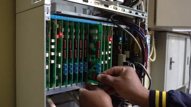 Technician or engineer changes the motherboard, PBX, telephone with flashing lights indicating the digital system connection