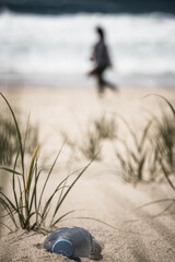 plastic bottle polluting the beach with tourists in the background