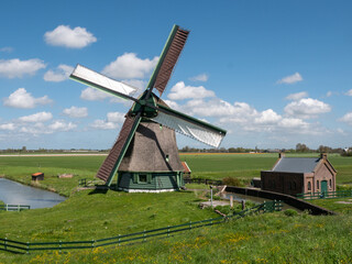 Fototapeta na wymiar Dutch windmill in polder landscape with beautiful clouds
