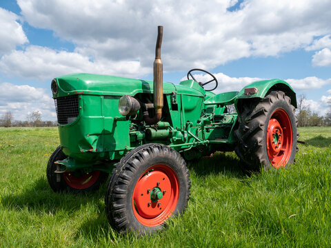 Old green tractor in Dutch polder landscape with beautiful clouds