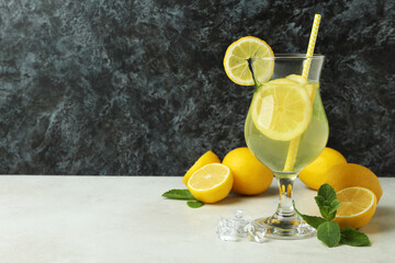 Glass of lemonade and lemons against black smokey background