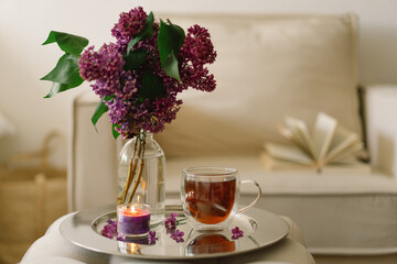 Still life details in home interior of living room. Lilac and cup of tea with candles.