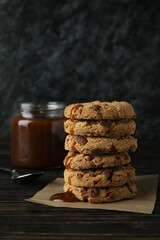 Caramel, spoon and cookies on wooden table