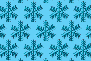 Decorative snowflakes pattern in modern style with hard shadows, flat lay. Toy snowflakes on a blue background in the form of a seamless pattern. Regular pattern.