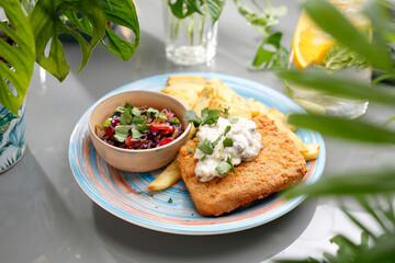 
Panko fried fish with tartar sauce, fries, and salad.
A colorful appetizing dish. Culinary photography, food styling.