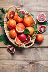 Pile of blood oranges in a basket on a wooden table background. Flat lay, top view, copy space